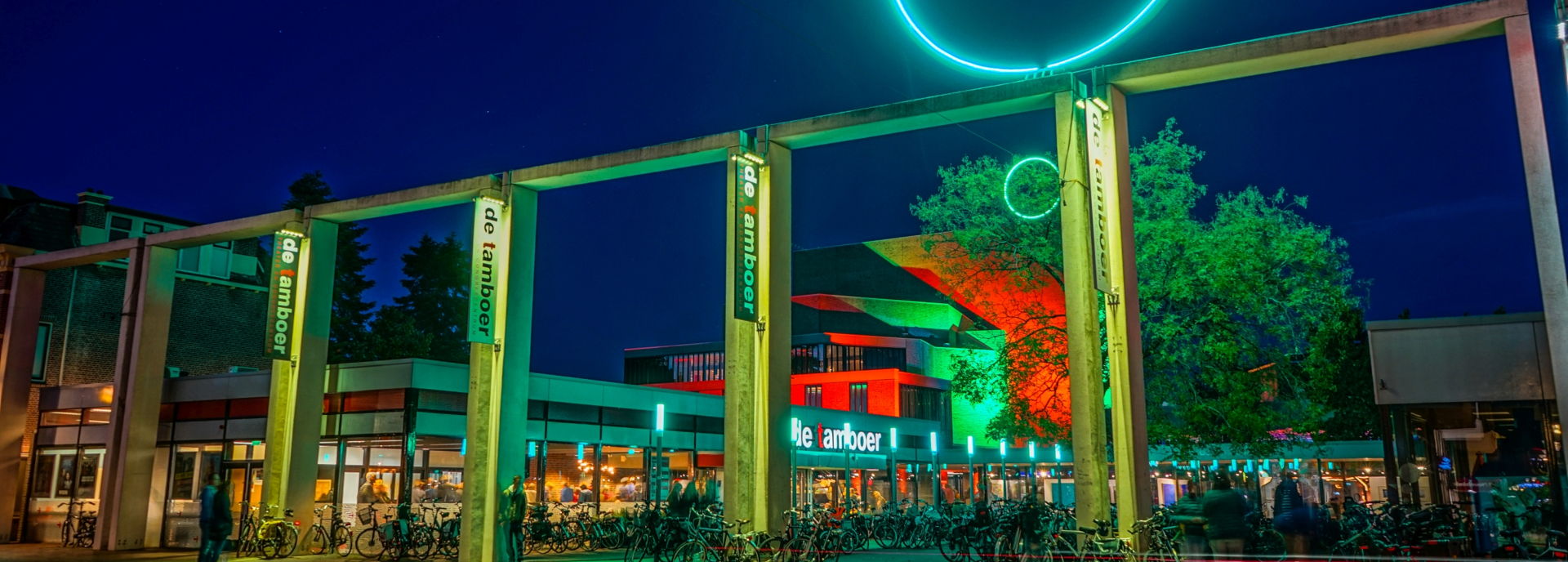 Het gebouw van Theater De Tamboer, gefotografeerd van buiten in de avond. 